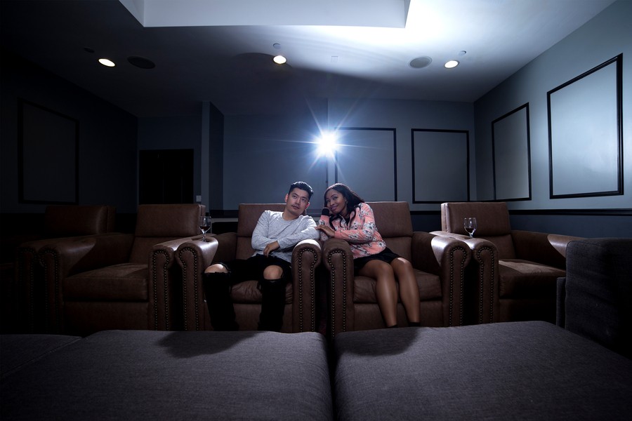 Couple sitting in a dark home theater with a projector in the background. 
