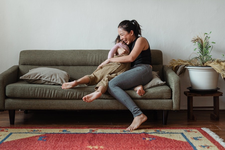Woman sitting on the couch hugging her child. 