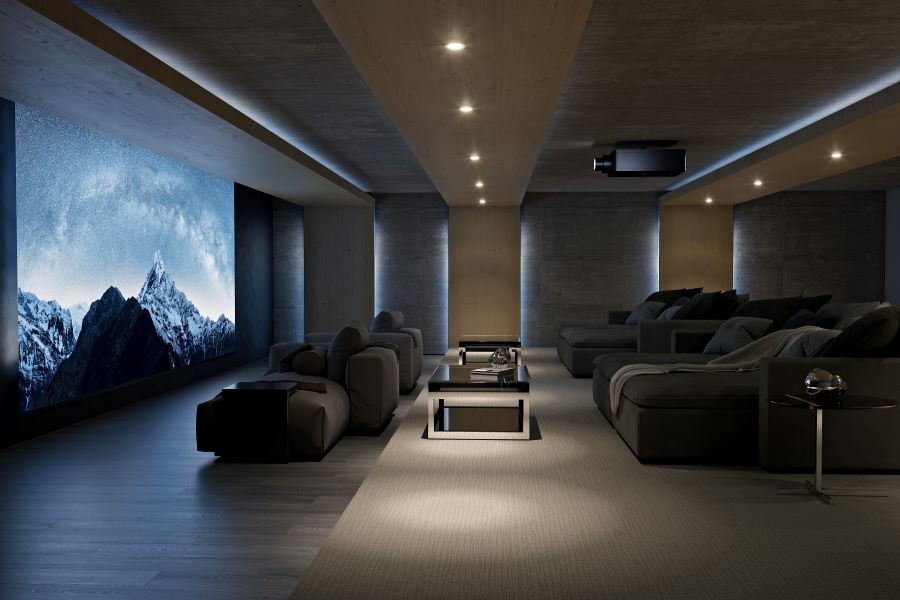 A large home theater with plush chaise lounges, a large screen, and a Sony projector.